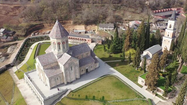 Scenic spring aerial view of monastic complex of Bodbe nunnery on hillside among tall Cypress trees with Church of St. Nino on sunny day, Sighnaghi, Georgia