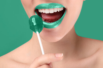 Beautiful young woman with mint lipstick and lollipop on color background, closeup