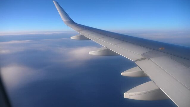 View from passenger window of wing of airplane flying in sky on sunny day. Concept of successful travel