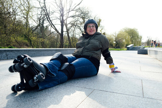 Woman resting on footpath with roller skates in park