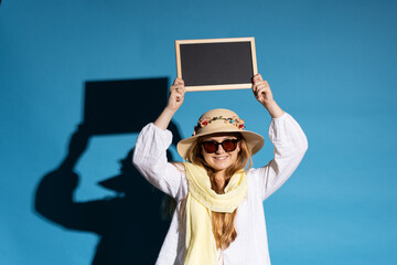 Tourist woman holding blackboard above in a sunny day isolated on blue background.