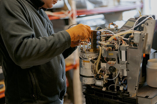 Professional worker fixing coffee machine in workshop