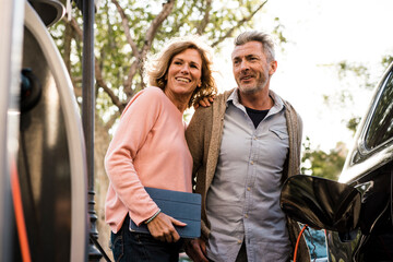 Smiling mature couple looking at charging station