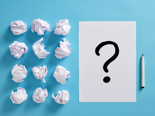 Question mark icon on a paper sheet with crumpled paper balls and a pen. Brainstorming and problem...