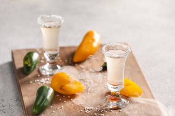 Shots of tasty mexican tequila with jalapeno pepper on light background