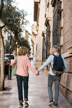Mature couple walking on footpath in city