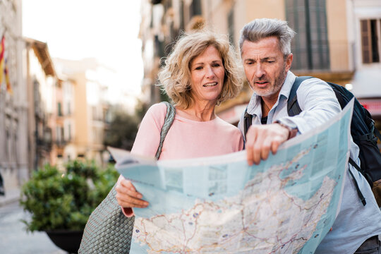 Mature man examining map with woman in city