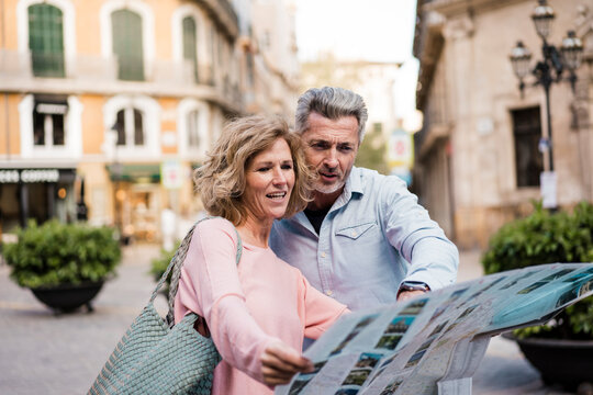 Mature couple reading map in city