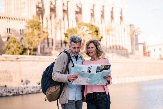 Mature couple with map standing in front of sea