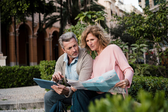 Mature couple with tablet PC examining map in park