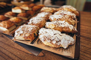 Freshly baked almond croissants with powdered sugar arranged on tray in bakery