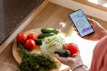 Woman holding smartphone with mobile app and vegetables