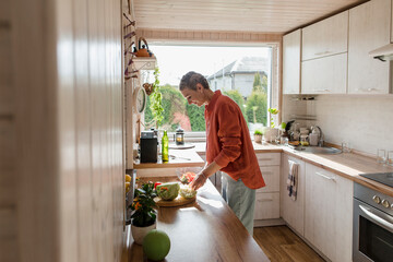 Woman preparing salad in kitchen at home