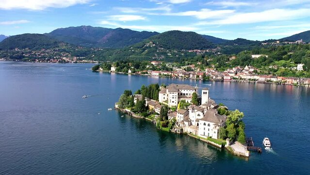 Flug &uuml;ber den Ortasee (Lago Orta) mit Blick &uuml;ber den See zur Insel San Giulio mit der mittelalterlichen historischen Basilika, Abtei und Kloster, Sommer, Sonne, blauer Himmel, Novara, Piemont, Italien