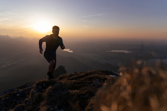 Silhouette hiker running on mountain at sunset