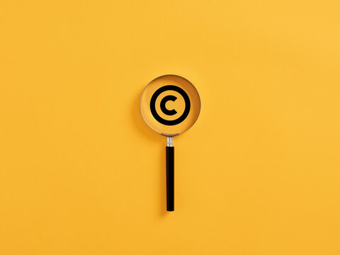 Magnifying glass magnifies copyright symbol. Patenting or copyright protection.