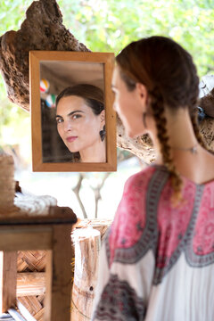 Woman looking in mirror on tree