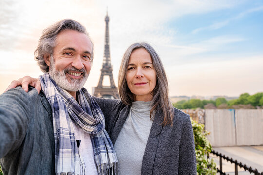 Happy man taking selfie with woman in front of Eiffel Tower, Paris, France