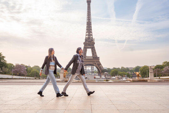 Mature couple holding hands and walking in front of Eiffel Tower, Paris, France