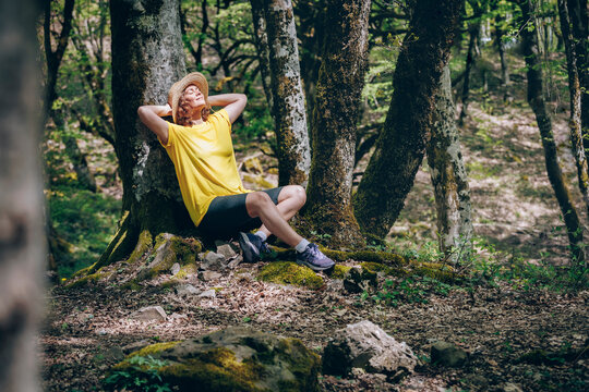 Woman leaning on tree relaxing in forest