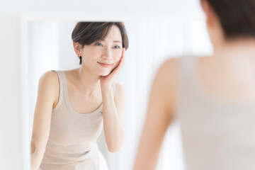 Obraz na płótnie Canvas 朝、鏡を見ながらスキンケアスキンケアをするアジア人女性