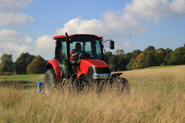 Red tractor cutting grass at a golf course in autumn