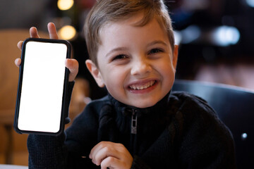 Smiling cute boy showing blank screen of mobile phone