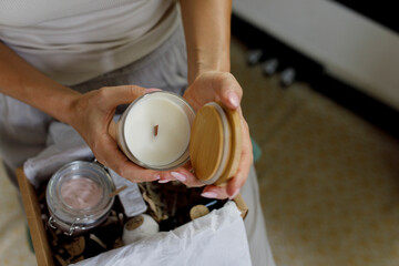 Hands of woman holding scented wax candle at home