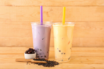 Plastic cups of tasty bubble tea on wooden background