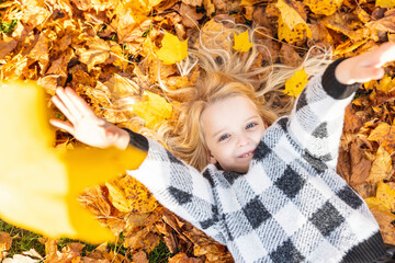 Playful girl lying on autumn leaves at park