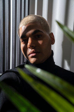 Young man with dyed blond short hair in front of wall