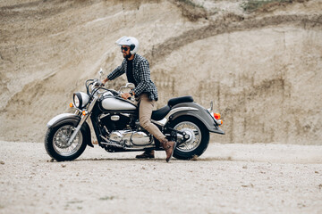 Handsome man with his moto in sand quarry