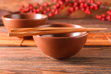 Chinese bowl with chopsticks on wooden background, closeup