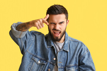 Bearded man pointing at viewer and winking on yellow background