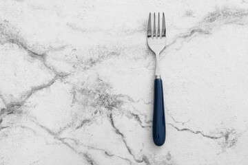 Stylish stainless steel fork on white marble background