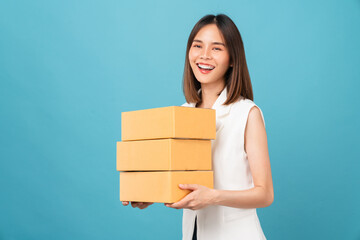 Smiling beautiful Asian woman holding cardboard boxes on blue background. Concept delivery online.