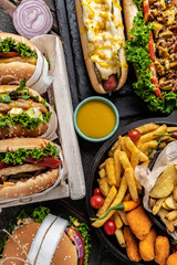 Close-up of home made tasty burger and hot dogs with fried chicken french fries. raditional American food. fast food. vertical image. top view
