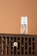 Liquid cosmetic product on a brick podium with a white flower. Cosmetic bottle with care product