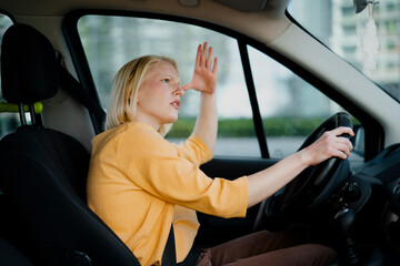 Fototapeta na wymiar Angry woman driving a car. Upset young woman driving car in city