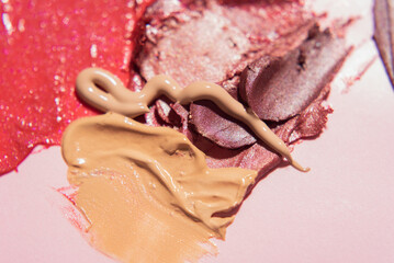 Smears of dark pink shimmery lipstick and beige face foundation. Texture and swatches of decorative cosmetics. Soft focus