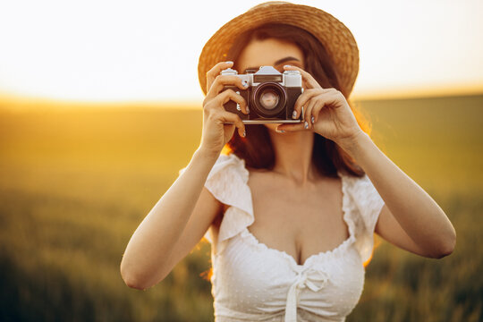 Young woman making photos with camera in the field