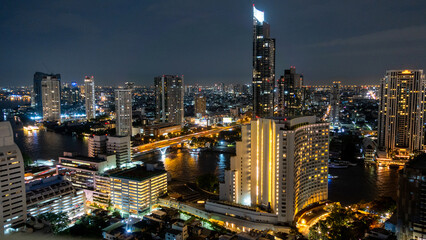 Fototapeta premium Beautiful panoramic city skyline in night.,cityscape view from high above.,The Lights of a Night City., Bangkok city skyline view from river with skyscrapers buildings reflect in water at night.