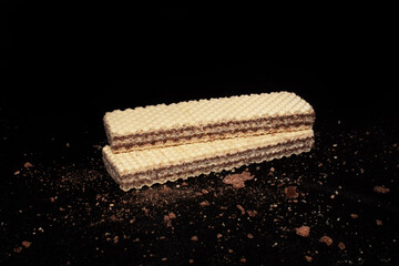 Cocolate wafers on dark background with broken wafers around 