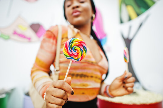 African american millennial lady at candy shop with lolipops.