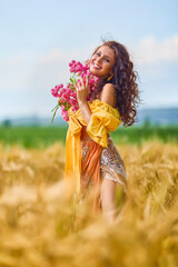 A young and beautiful Caucasian woman happy with a bouquet of flowers in a field.