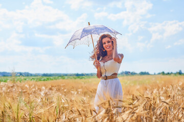 A beautiful woman on a sunny day with an umbrella in a field.