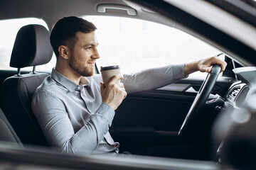 Man drinking coffee and driving a car