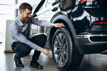 Man choosing a car and checking tires