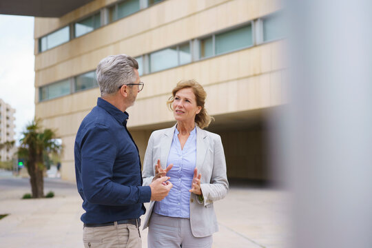 Businesswoman discussing with businessman in front of office building