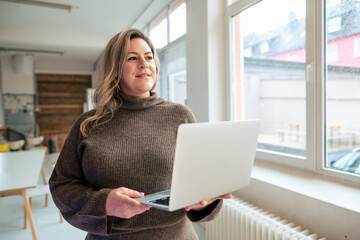 Thoughtful plus size businesswoman with laptop at office